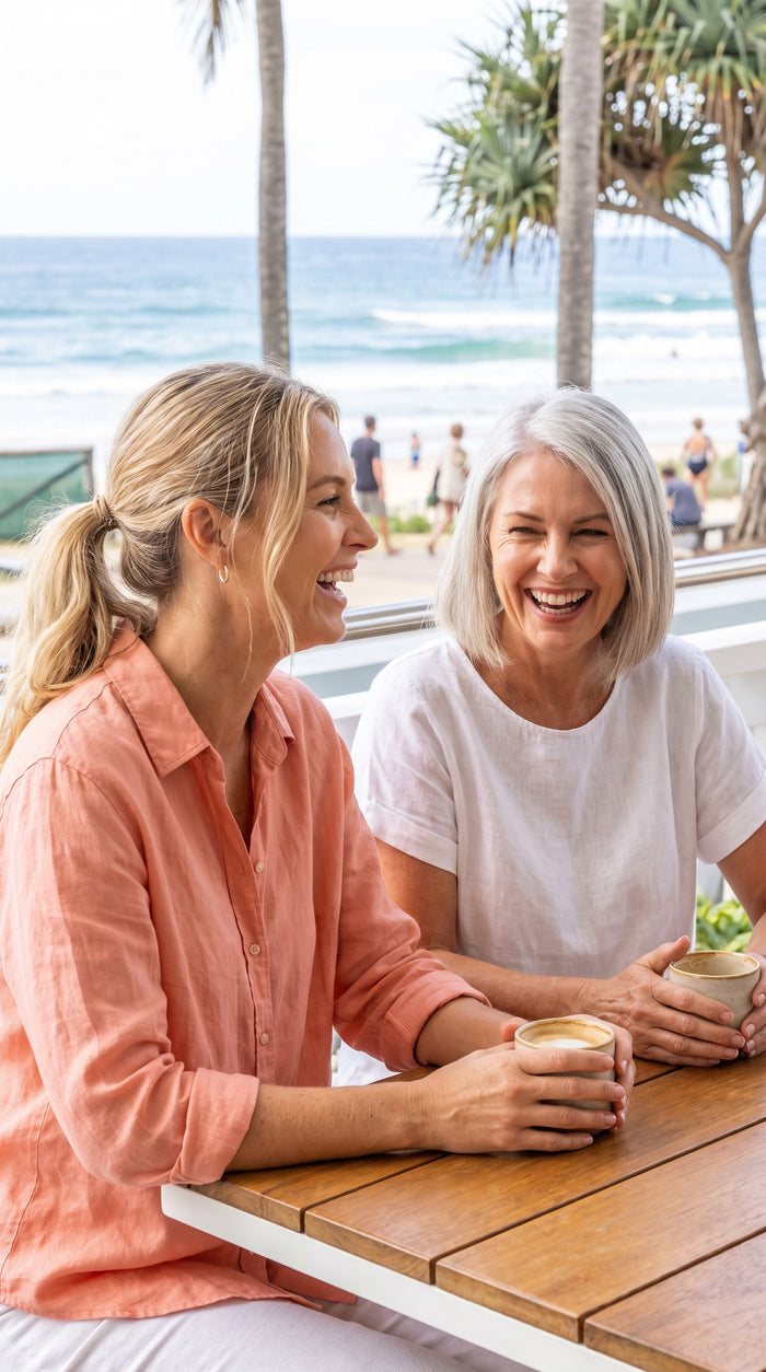 Two friends laughing at a beachside brunch