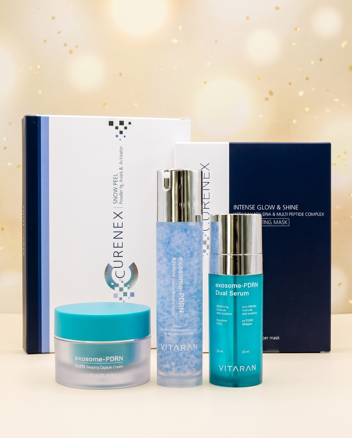 The Ultimate Glow Gift Set, skincare collection with white and navy packaging, turquoise cream jar and serum bottles, and sheet masks.