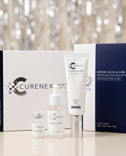 The Glow Night In Gift Set with white skincare tubes, glass dropper bottles and navy sheet mask box, packaged together.